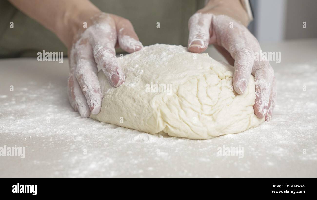 Mains façonnant la pâte en boule à la main. Chef préparant la pâte pour la cuisson du pain à pizza dans le restaurant, la cuisson Banque D'Images