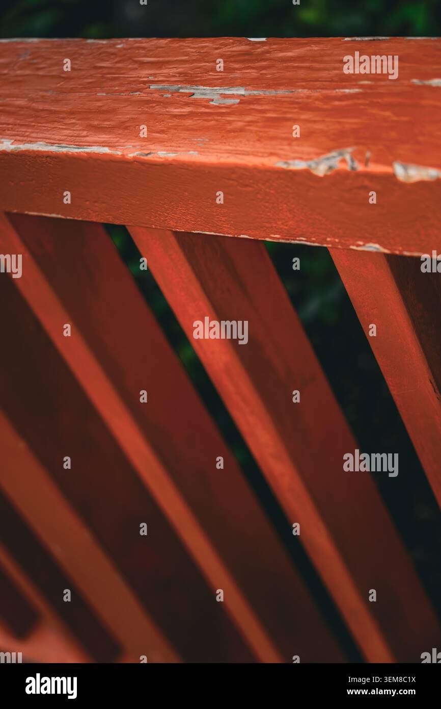 Gros plan d'une structure en bois peinte en rouge présentant des lattes diagonales, une composition géométrique et une texture de surface usée. Détail architectural avec pelage Banque D'Images