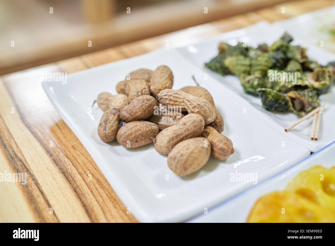 Les cacahuètes non décortiquées reposent sur une assiette blanche dans un cadre coréen. Ce gros plan capture à merveille le charme authentique du naturel, non traité Banque D'Images