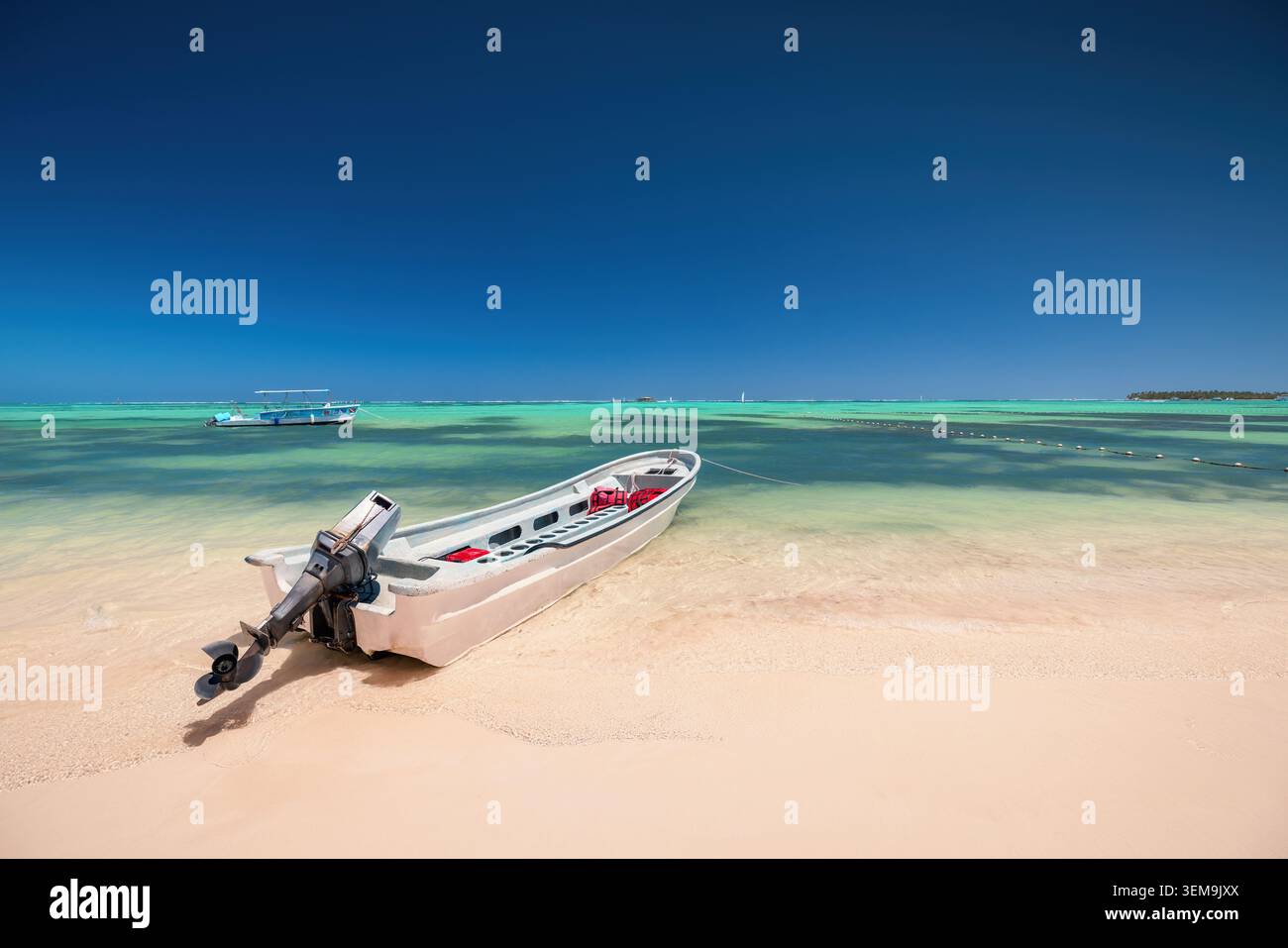 Petit bateau à moteur avec moteur hors-bord amarré sur une plage tropicale de sable blanc à côté de l'eau turquoise Banque D'Images