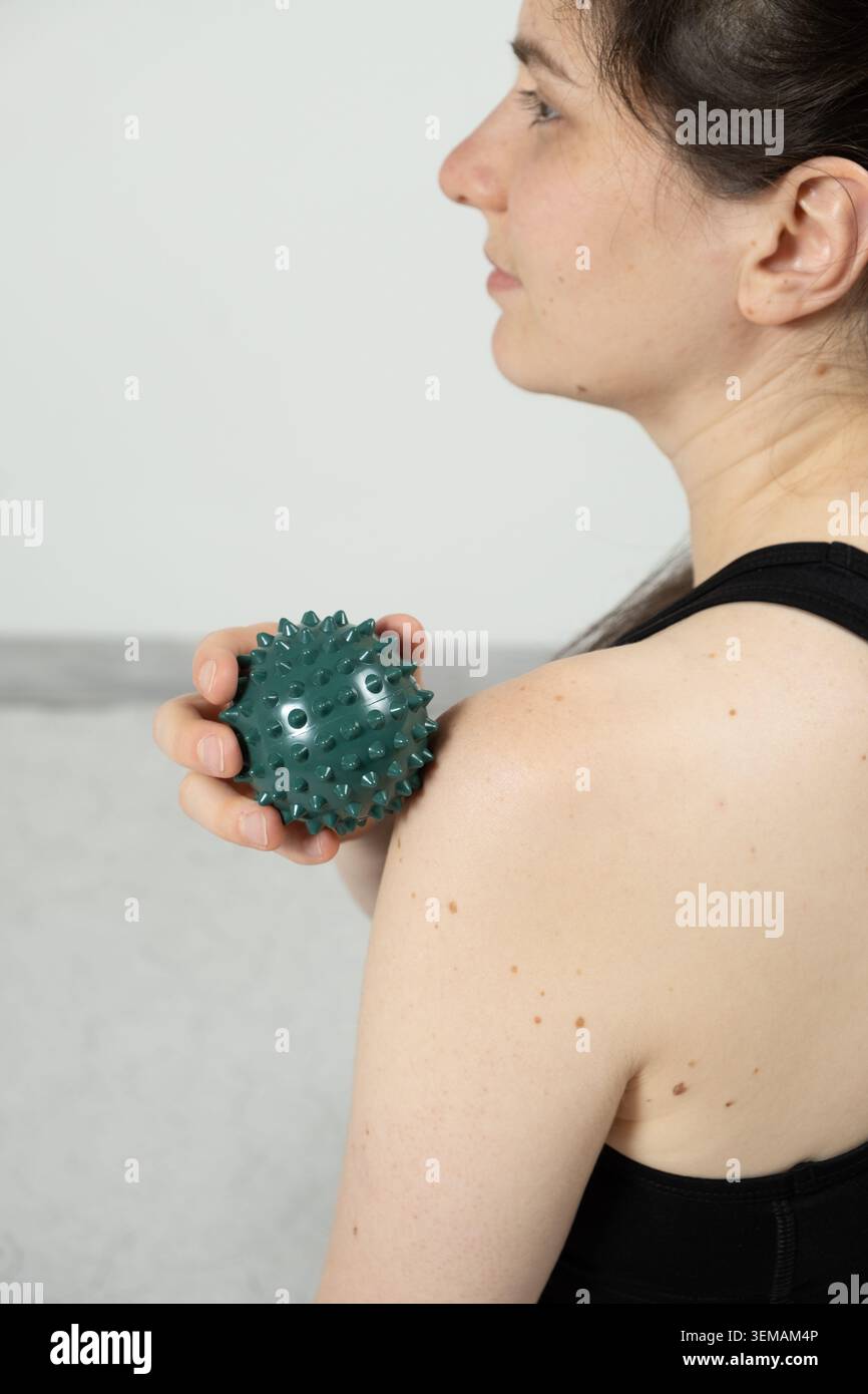 Femme utilisant la boule de massage pour le soulagement de la douleur de l'épaule Banque D'Images