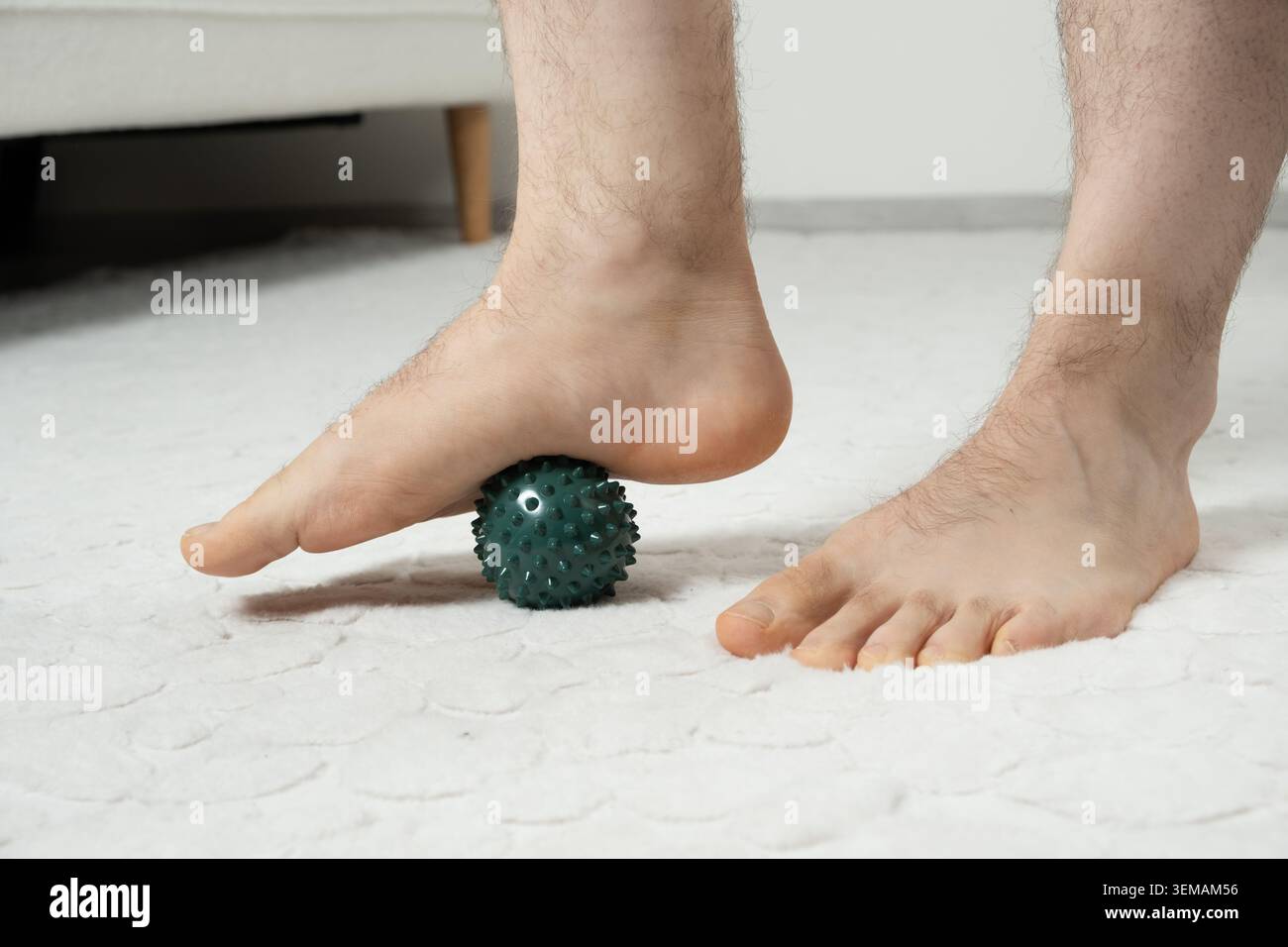 Gros plan d'un homme marchant pieds nus sur la balle de massage d'acupuncture pour la thérapie Banque D'Images