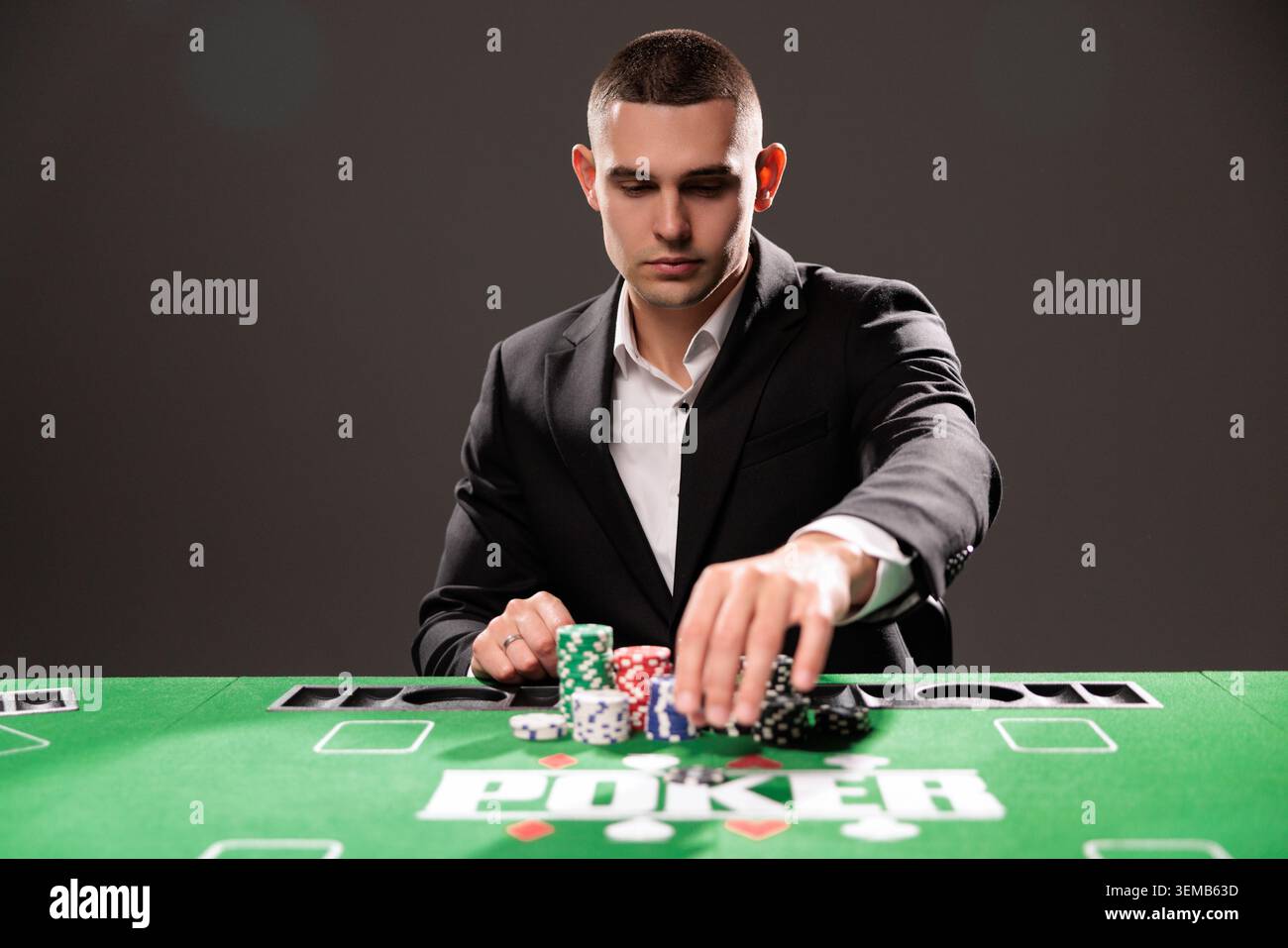 Beau barbu homme joue au poker assis à la table dans le casino. Banque D'Images