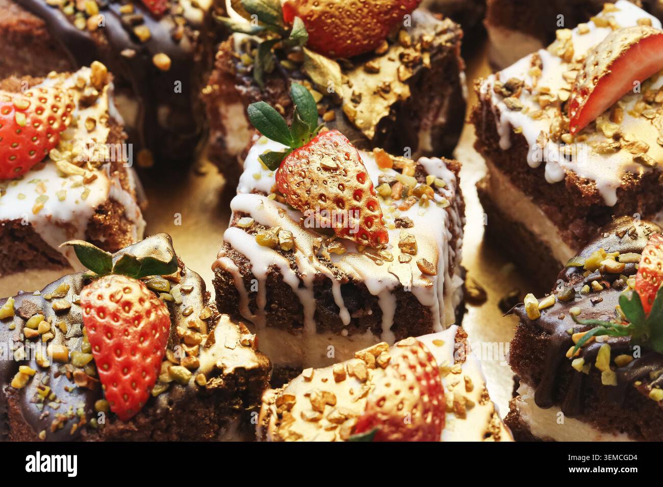 Bouchées de cheesecake au chocolat décorées avec fraises et flocons d'or. Fond de dessert gastronomique pour les célébrations de restauration et les buffets sucrés. Banque D'Images