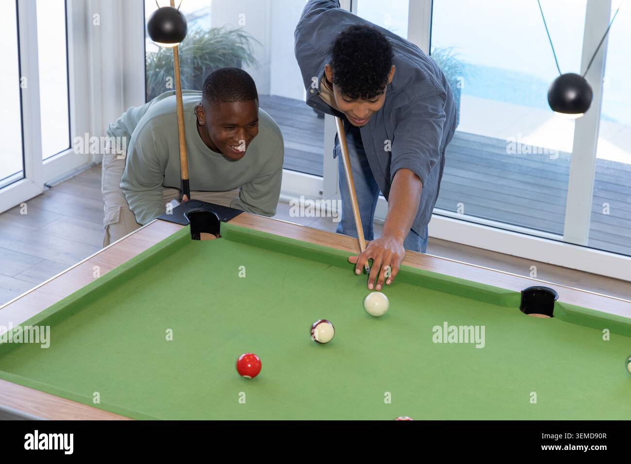 Divers amis masculins alignant la piscine sur la table de feutre vert dans la salle de jeux avec des repères Banque D'Images