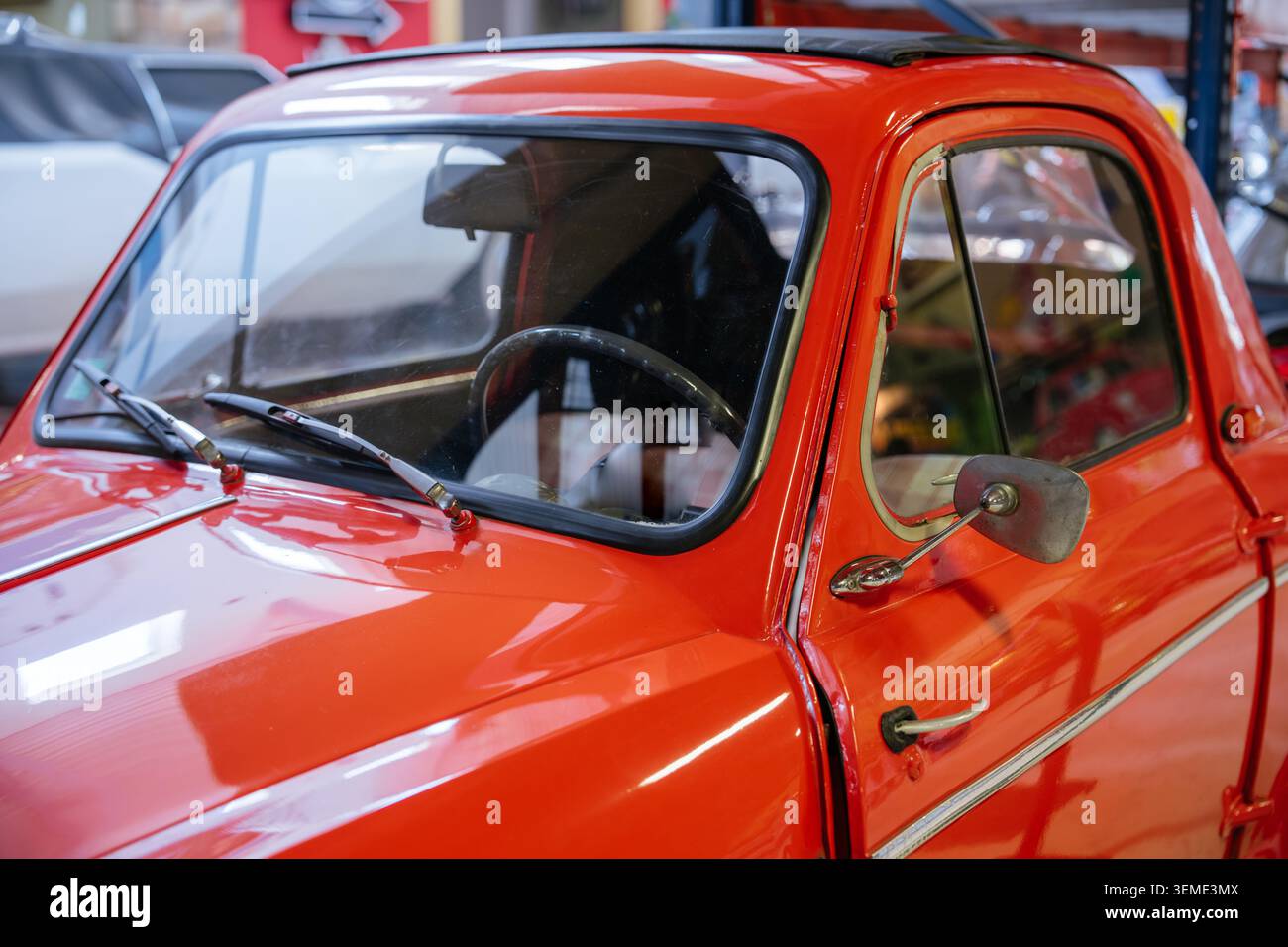 Un gros plan capture une voiture vintage rouge éclatante présentant des caractéristiques extérieures polies. Parmi les caractéristiques principales, mentionnons le pare-brise, les essuie-glaces, les rétroviseurs extérieurs, les poignées de porte Banque D'Images