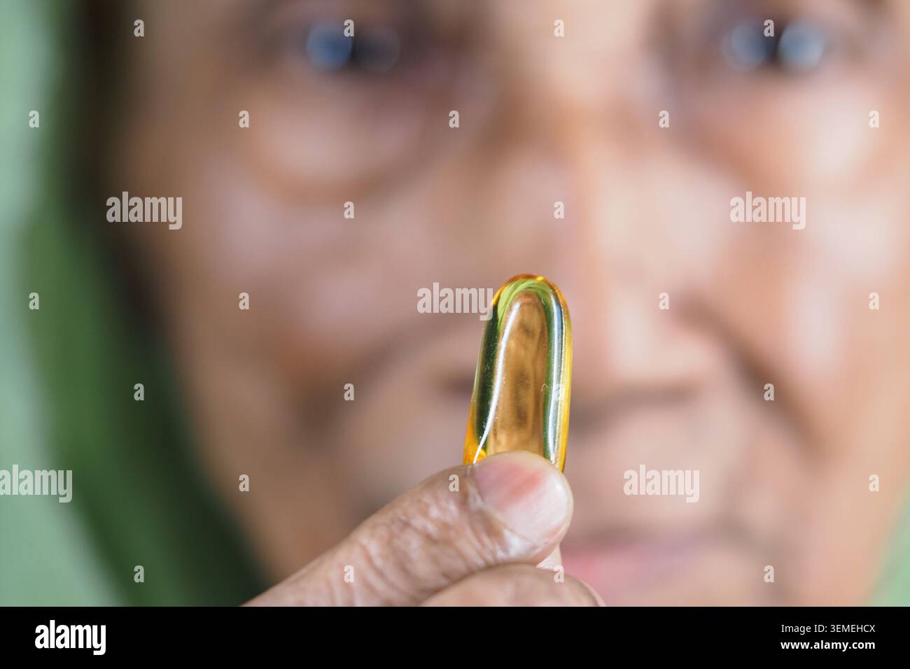 Femme âgée tenant une capsule d'huile de poisson dans un gros plan Banque D'Images