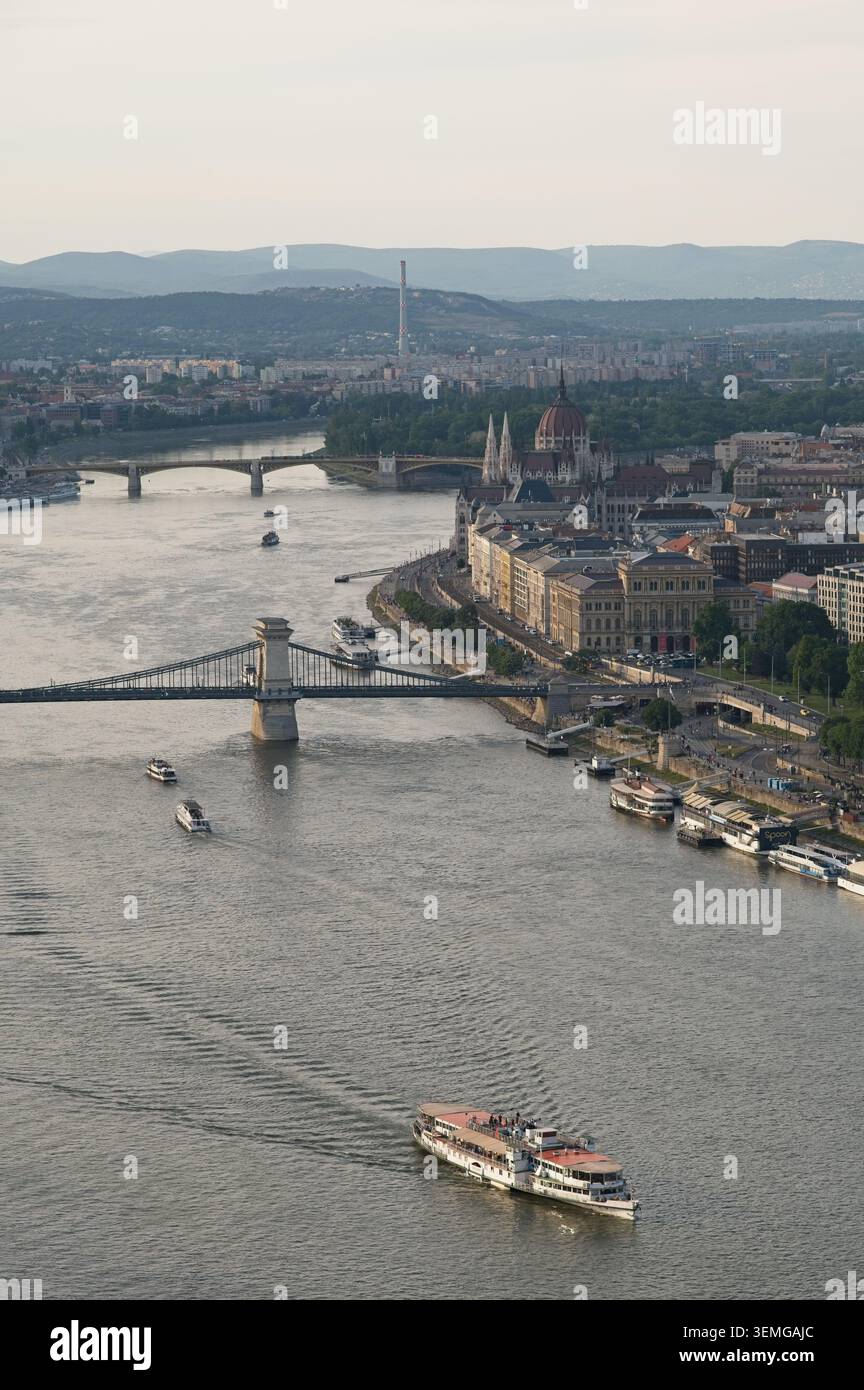 Budapest, Hongrie - 31 mai 2026 : vue verticale d'un bateau de croisière sur le Danube avec le pont des chaînes et le bâtiment du Parlement dans la soirée. Banque D'Images