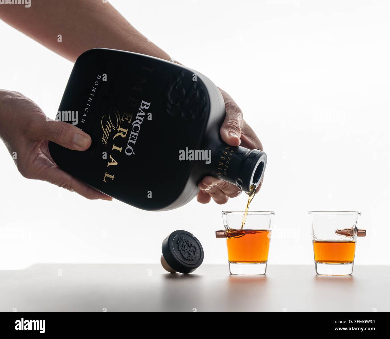 Barcelo Imperial rhum étant versé dans des verres à dose sur fond blanc, boisson de liqueur des Caraïbes, dégustation d'alcool et concept éditorial de bouteille de marque. Banque D'Images