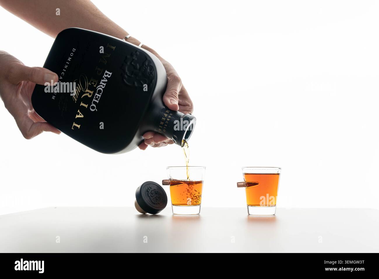 Barcelo Imperial rhum étant versé dans des verres à dose sur fond blanc, boisson de liqueur des Caraïbes, dégustation d'alcool et concept éditorial de bouteille de marque. Banque D'Images