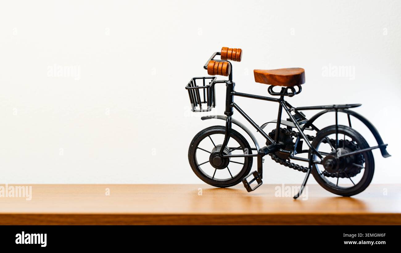 Vélo miniature décoratif sur fond blanc avec siège en bois, petit modèle de vélo vintage pour la décoration intérieure, le style de vie, le jouet et les concepts créatifs aujourd'hui Banque D'Images
