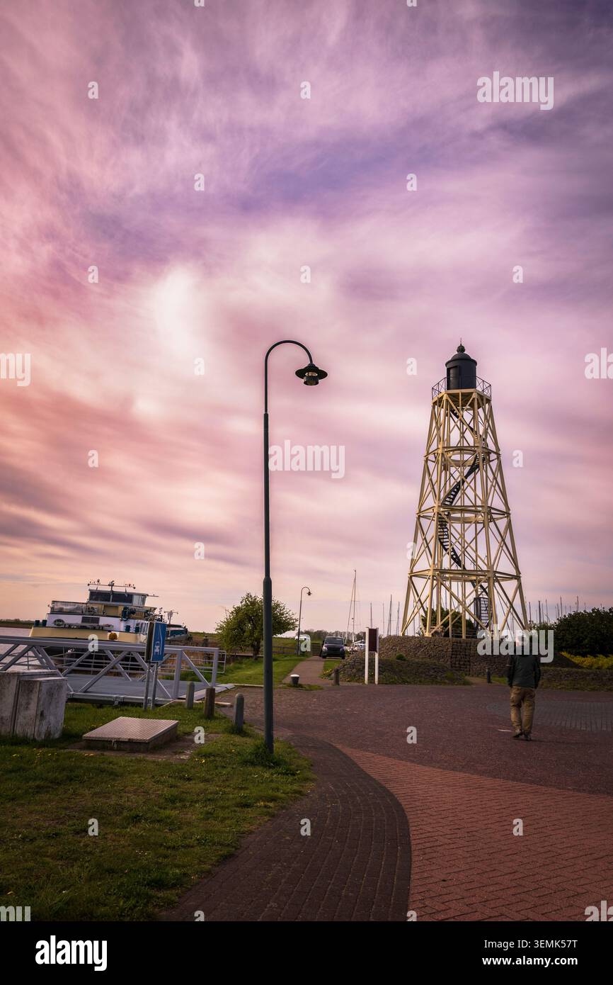 Tour de phare en métal dans le port de Lemmer, pays-Bas, avec un bateau à côté. Une scène maritime mêlant structure de navigation et vie portuaire. Banque D'Images