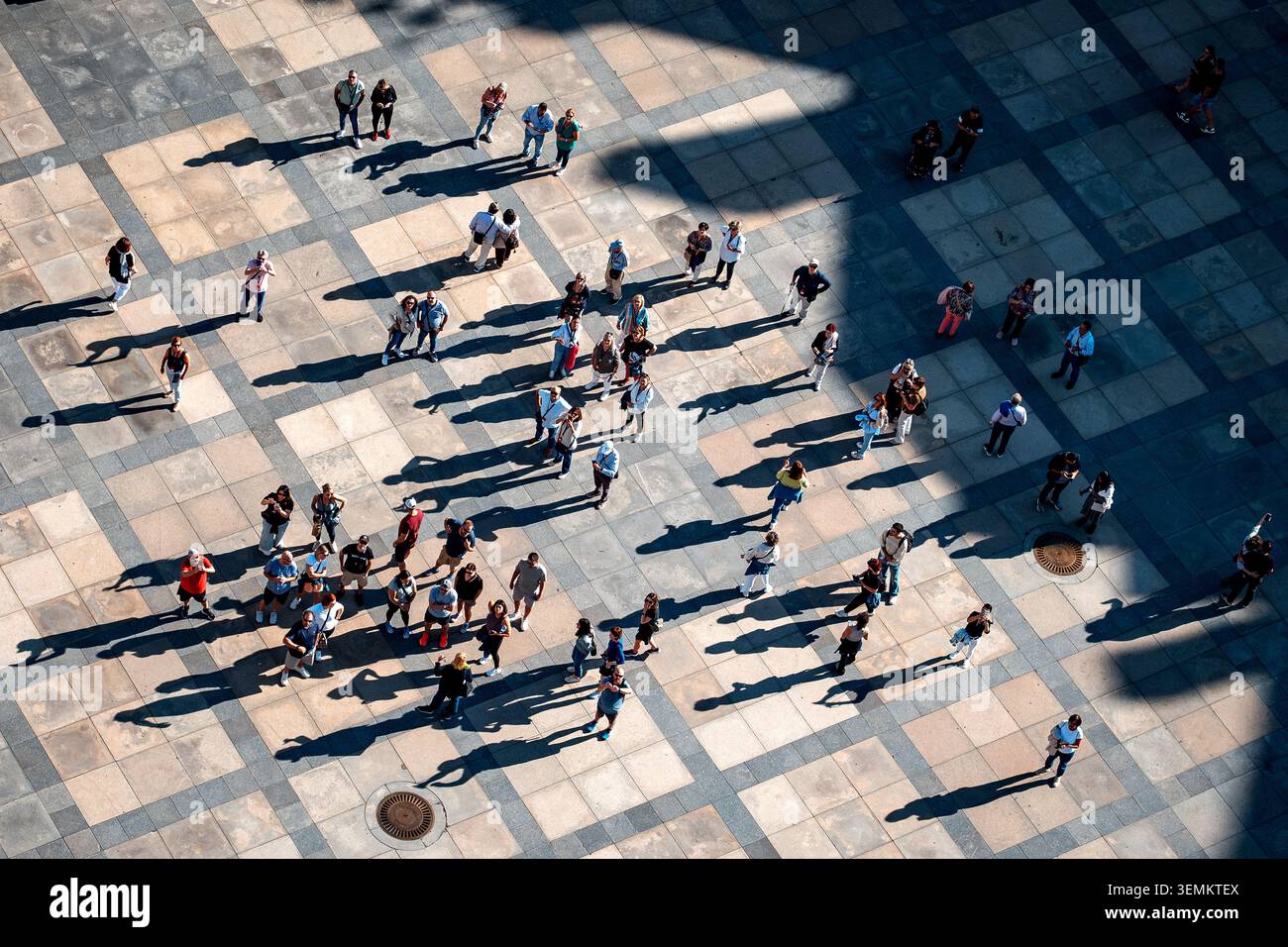 Vue aérienne des piétons projetant de longues ombres sur la place ensoleillée Banque D'Images