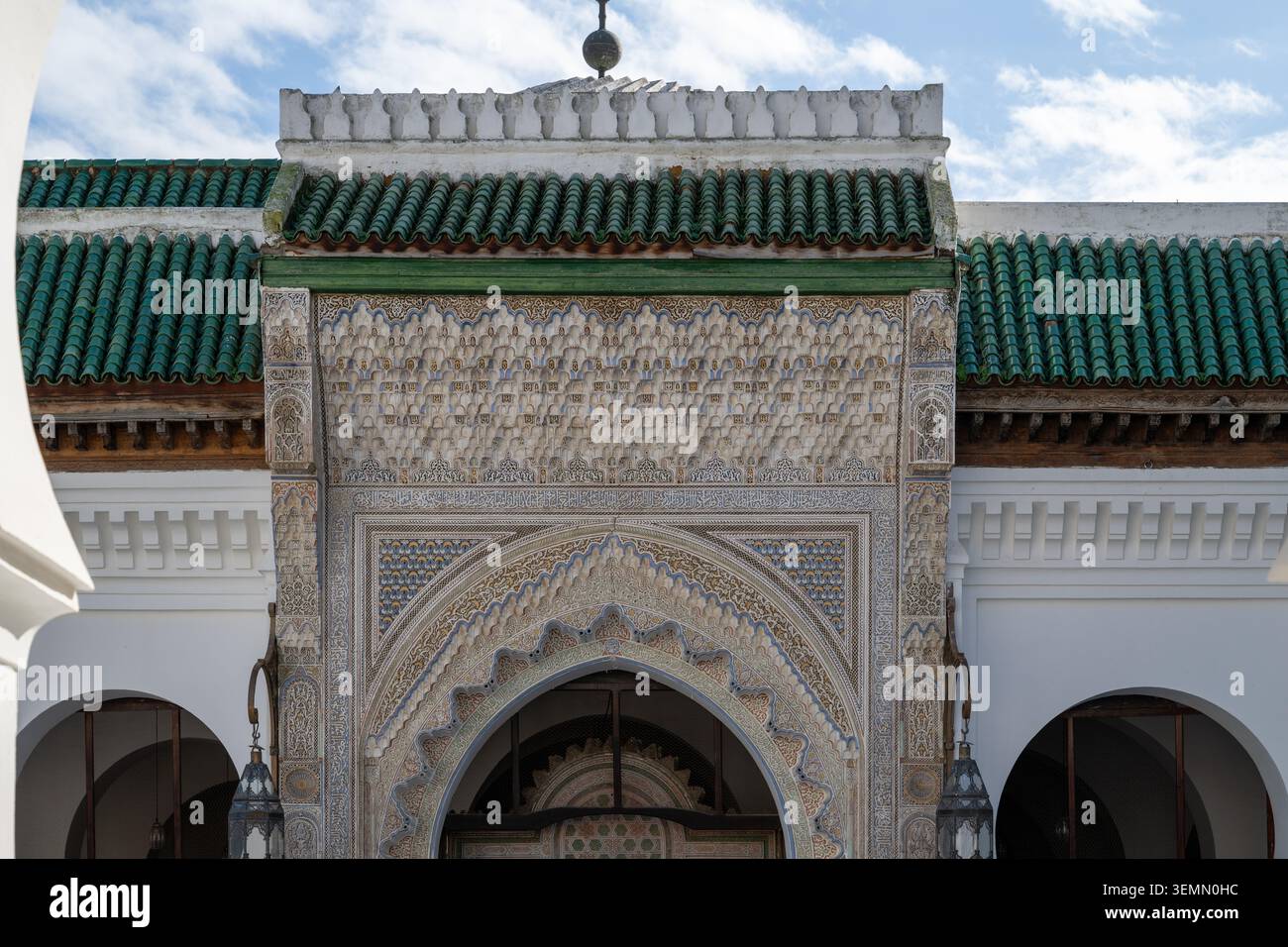 L'entrée islamique ornée de Fès présente du stuc sculpté complexe, une décoration géométrique, des arches en fer à cheval, des murs blancs et des toits en tuiles vertes. Banque D'Images