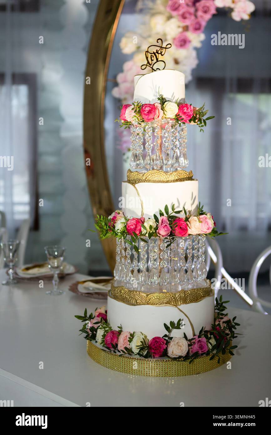 Un grand gâteau de mariage à plusieurs niveaux est placé sur une table le gâteau est orné de fleurs et d'éléments décoratifs le cadre comprend un cha élégant Banque D'Images