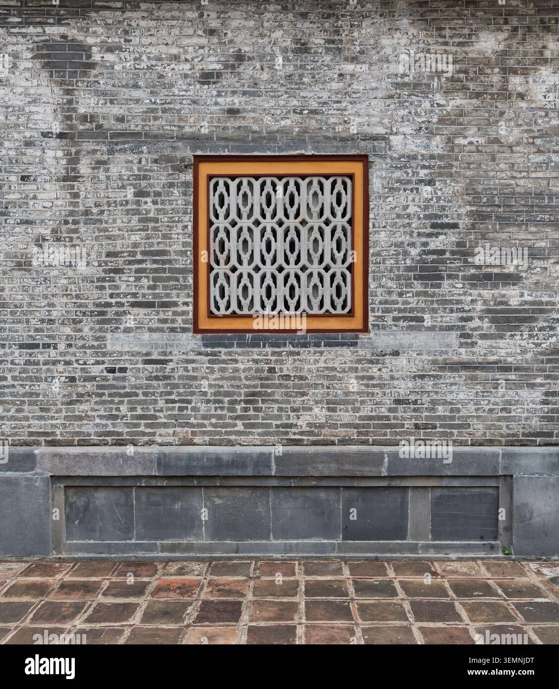 Mur de briques altérées avec une fenêtre décorative à motifs géométriques et une base en pierre, ville impériale, Hué, Vietnam Banque D'Images