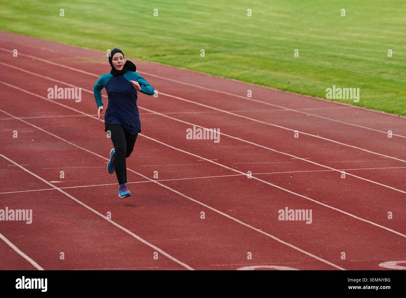 Athlète féminine qui court sur une piste extérieure portant des vêtements de sport et un foulard pendant la séance d'entraînement Banque D'Images