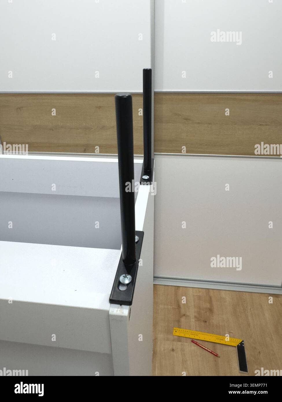 Deux pieds en métal noir installés debout sur le coin de l'armoire à chaussures blanches pendant l'assemblage Banque D'Images