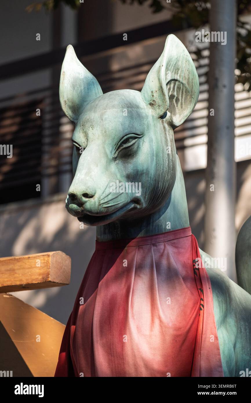 Vue rapprochée d'une statue de renard en pierre portant un bavoir rouge dans un sanctuaire shinto, Tokyo, Japon Banque D'Images