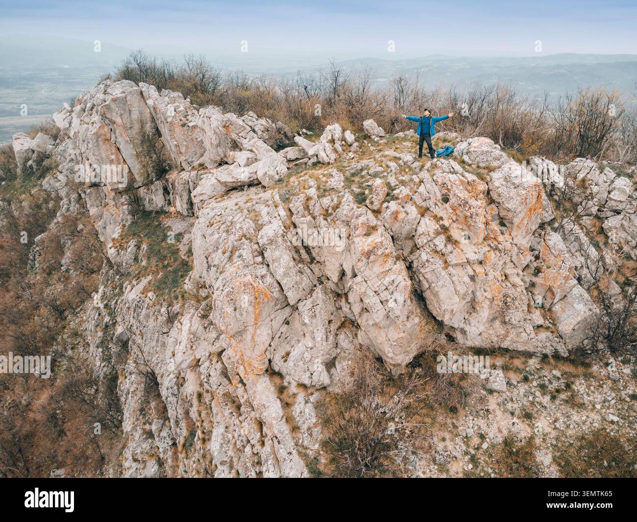 Homme debout sur le sommet de la montagne avec les bras grands ouverts, célébrant la réalisation et profitant du paysage sauvage Banque D'Images