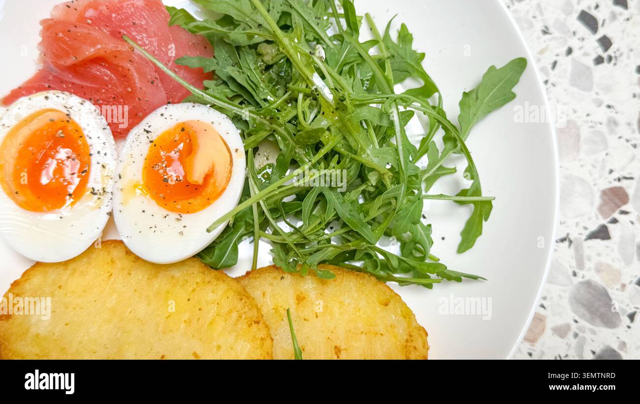 Assiette de petit déjeuner au saumon fumé avec œufs durs, arugula et crêpes de pommes de terre, pour des menus de petit déjeuner sains, plats visuels minutieusement, promoti brunch Banque D'Images