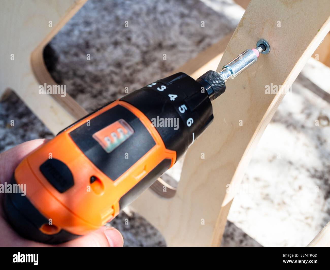carpenter assemble des meubles en bois à l'aide d'un tournevis électrique à l'extérieur gros plan Banque D'Images