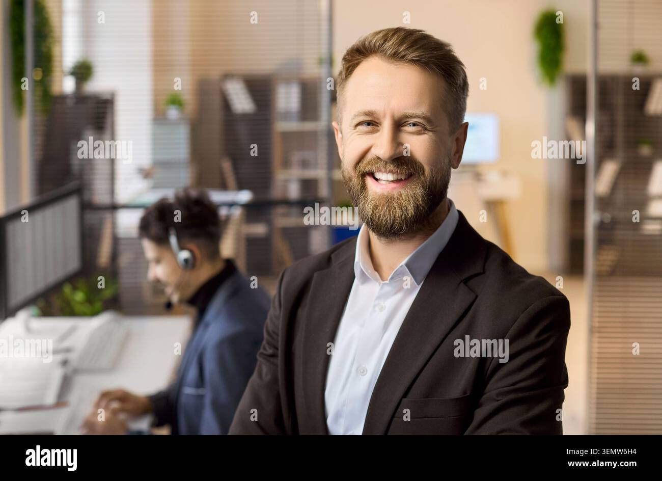 Portrait de gestionnaire d'homme d'affaires souriant dans un bureau moderne avec un collègue aux ordinateurs Banque D'Images