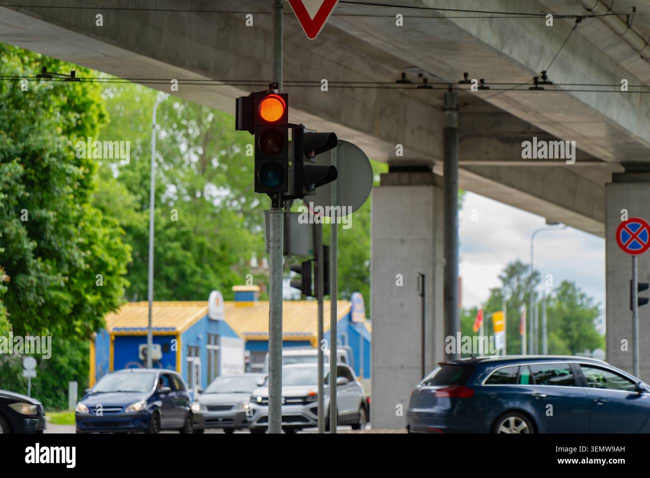 Carrefour de transport urbain comportant un système de feux stop fixé sur un poteau en acier sous une lourde structure de survol d'autoroute avec voiture active Banque D'Images