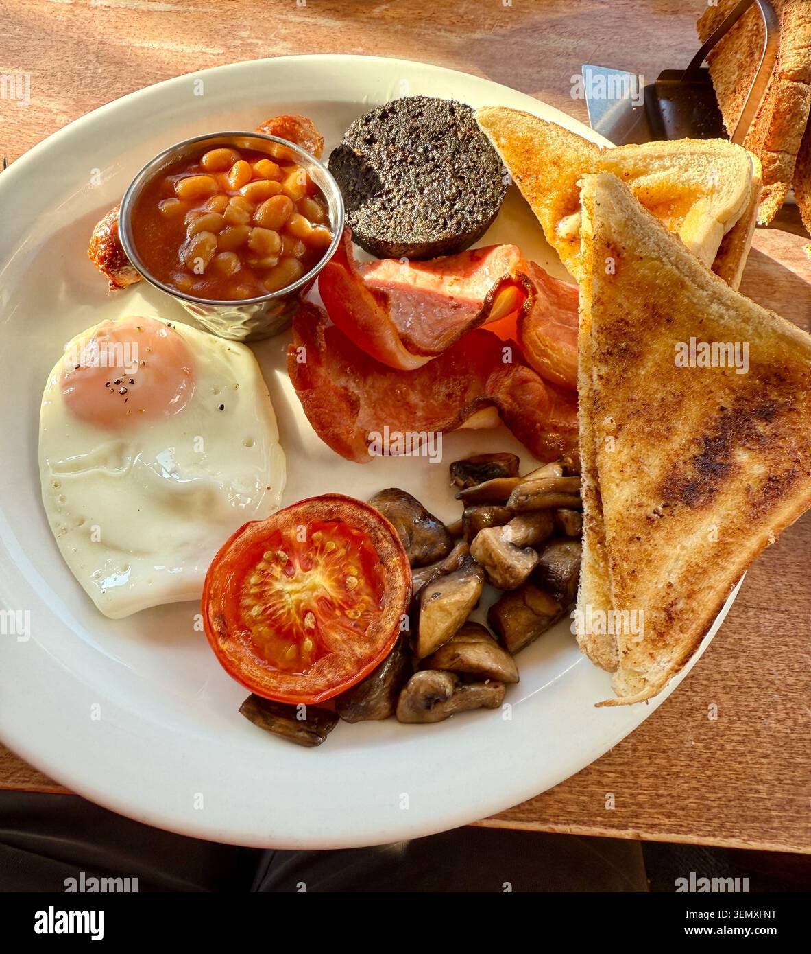 Un petit-déjeuner écossais complet avec pudding noir, haricots, œufs et pain grillé sur une assiette blanche. - Image de stock capturée avec un smartphone