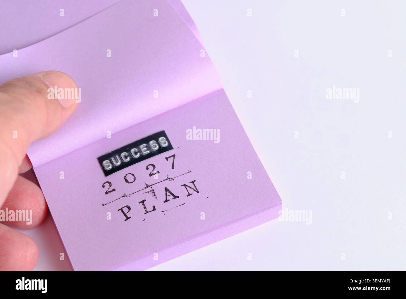 La main ouvre le bloc-notes violet affichant les mots estampillés SUCCESS PLAN 2027 en gros PLAN propre Banque D'Images