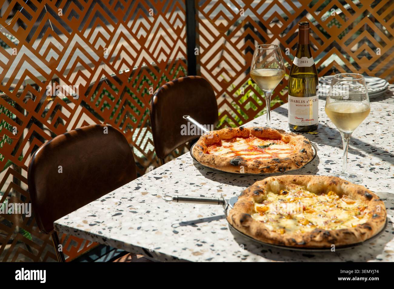 Délicieuses pizzas servies avec du vin à une table à manger extérieure moderne Banque D'Images