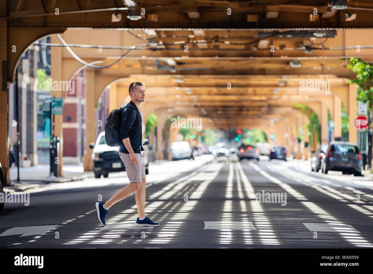 Homme traversant la rue de la ville sous l'infrastructure de voie ferrée surélevée dans le centre-ville de Chicago. Style de vie urbain, sécurité des piétons, déplacements urbains et Banque D'Images