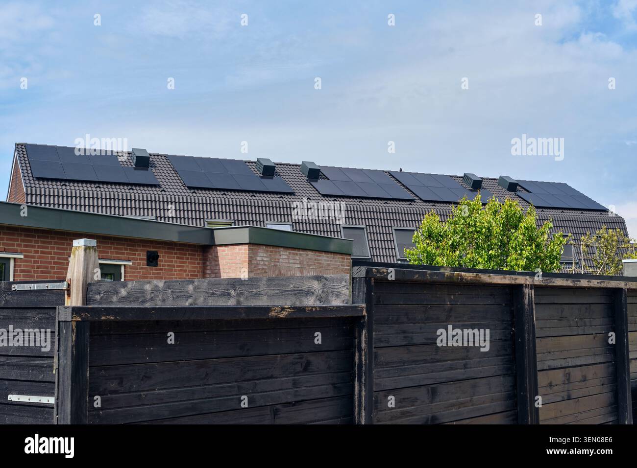 Solution d'énergie durable avec plusieurs panneaux solaires installés sur les toits de tuiles sombres des maisons résidentielles à Den Oever, pays-Bas. Banque D'Images