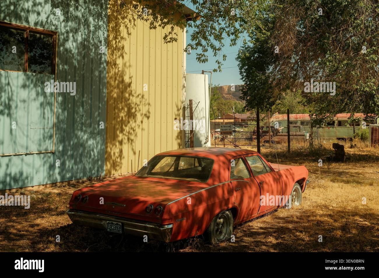 Voiture rouge d'époque abandonnée à côté d'un bâtiment à Bluff, Utah, États-Unis, reflétant l'héritage routier du sud-ouest américain. Banque D'Images