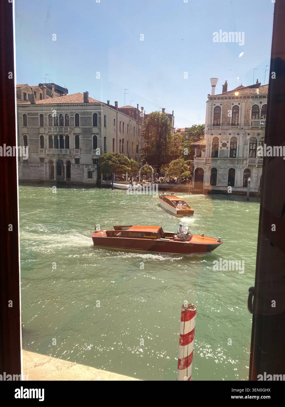 Chambre avec vue : les taxis aquatiques filent le long du Grand Canal devant les élégants palais, Venise, Italie - Image de stock capturée avec un smartphone