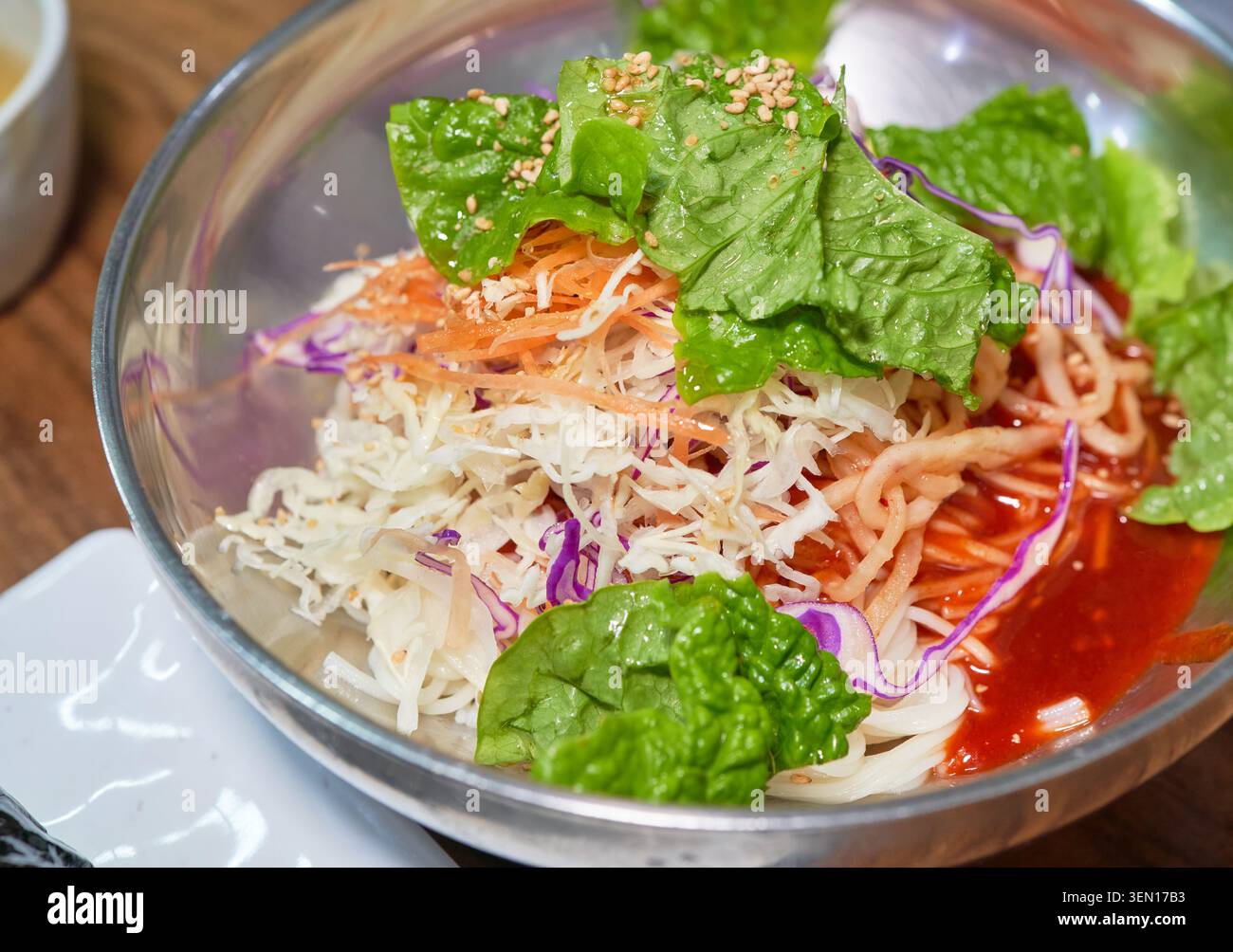 Soupe traditionnelle coréenne chaude aux nouilles, rouleau de riz aux algues tranchées et nouilles épicées mélangées aux légumes frais servies dans d'authentiques bols en acier inoxydable. Banque D'Images