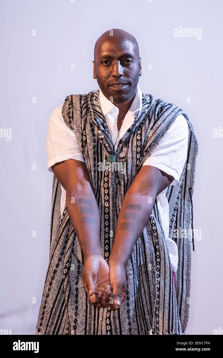 Kei Miller se tient dans un studio, les bras tendus vers l'avant, mettant en valeur un geste qui invite le spectateur à interagir. Banque D'Images