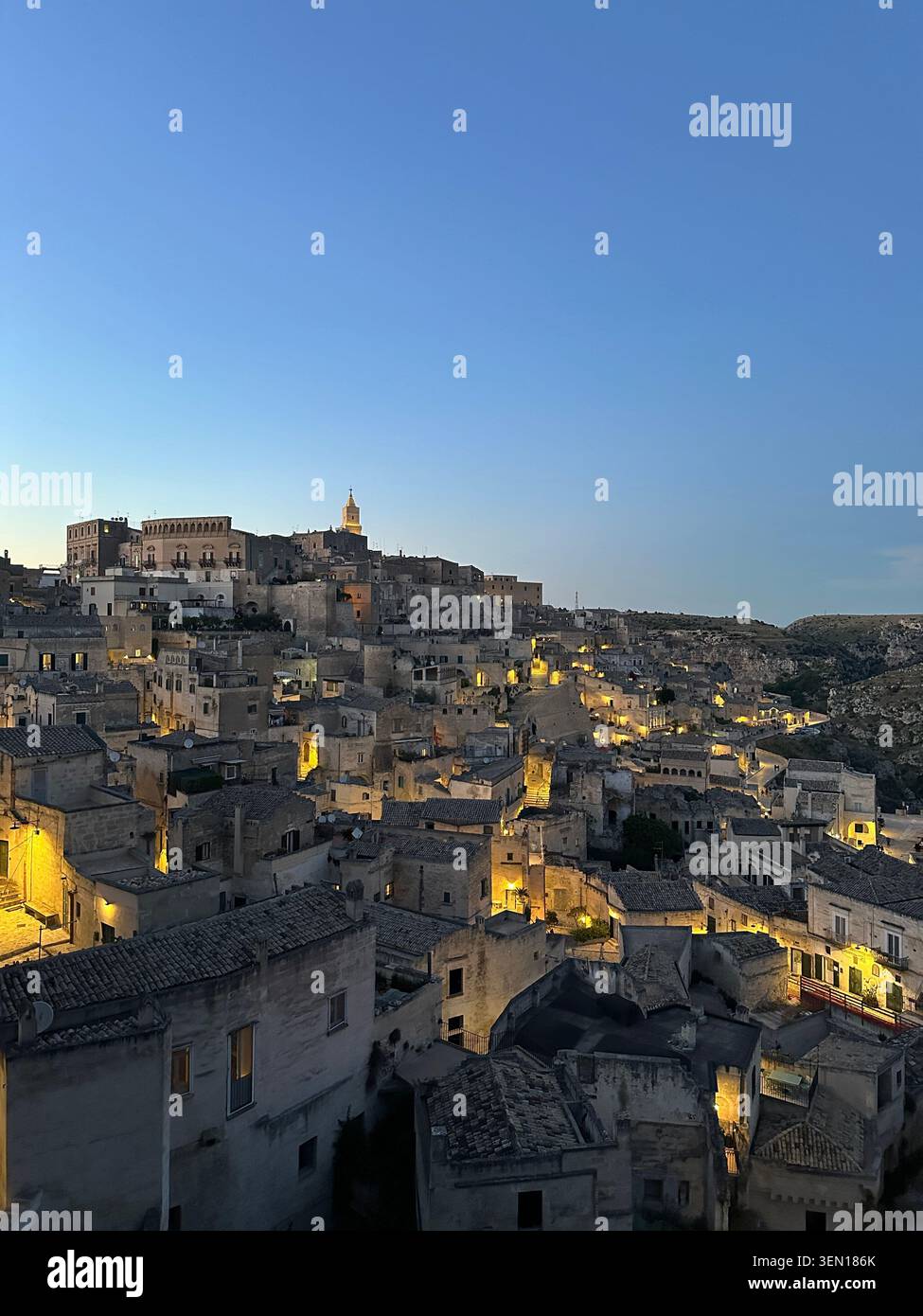 Les lumières dorées s'éveillent à travers le labyrinthe de pierre de Matera alors que le crépuscule descend sur l'ancien quartier des Sassi. - Image de stock capturée avec un smartphone