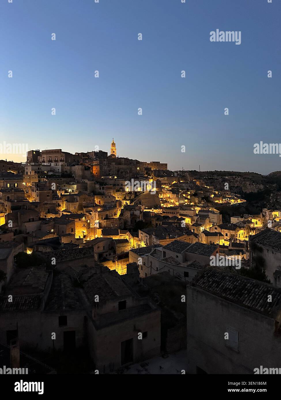Matera brille comme une constellation taillée dans la pierre, ses anciennes habitations des Sassi dévalant sous le ciel de l'heure bleue. - Image de stock capturée avec un smartphone