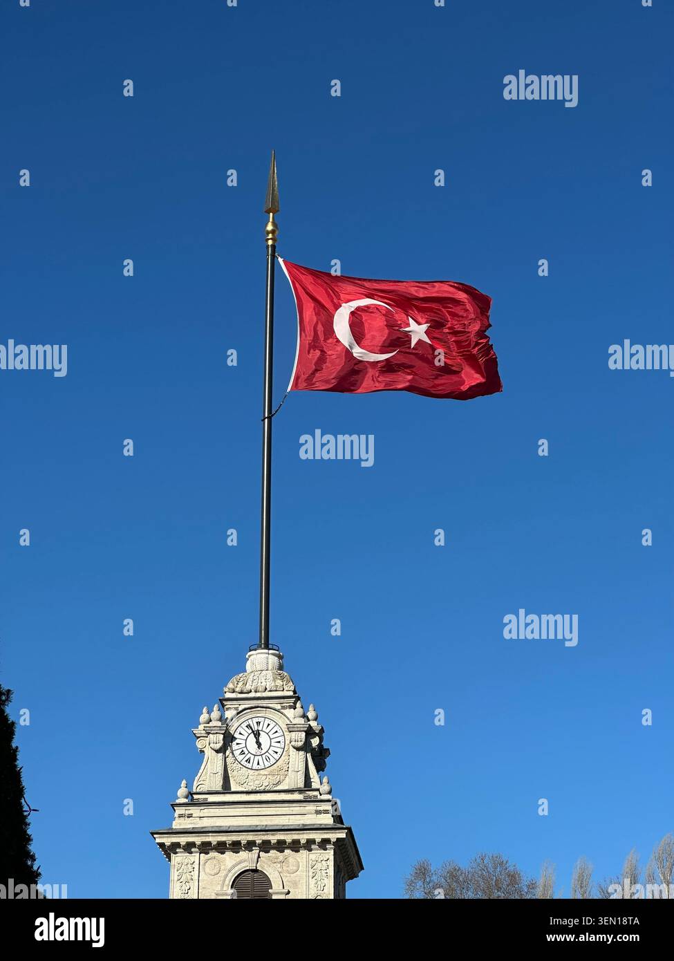 Drapeau turc flotte au-dessus d'un monument orné contre un ciel bleu impeccable à Istanbul. - Image de stock capturée avec un smartphone