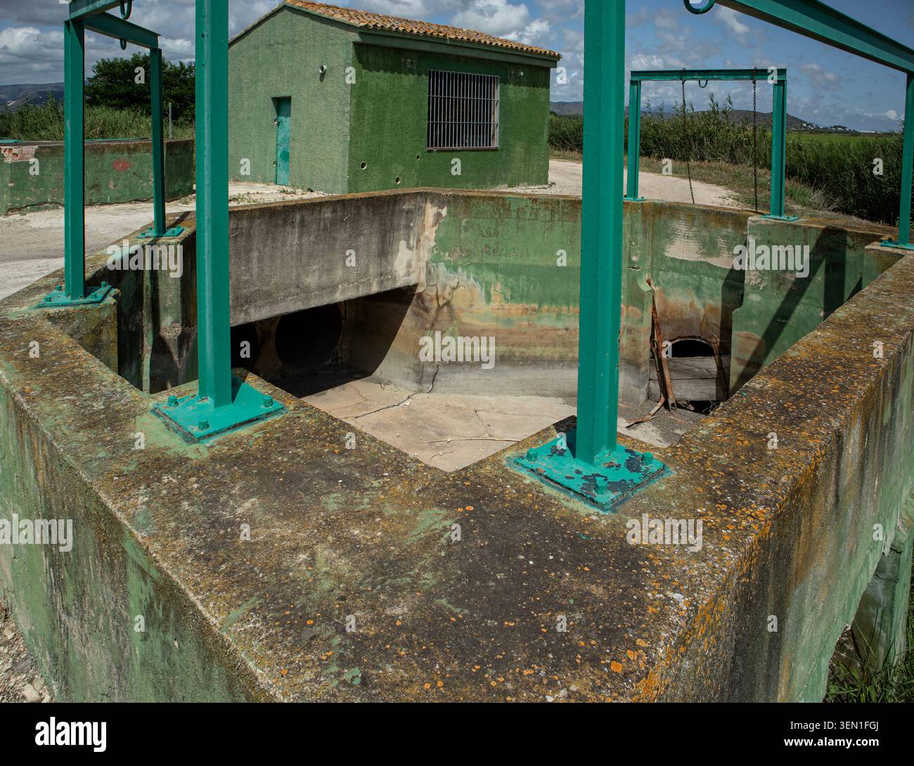 Le puits de distribution d'eau en béton ouvert est relié à une pompe verte. Cette configuration prend en charge le système d'irrigation d'une vall agricole espagnole Banque D'Images