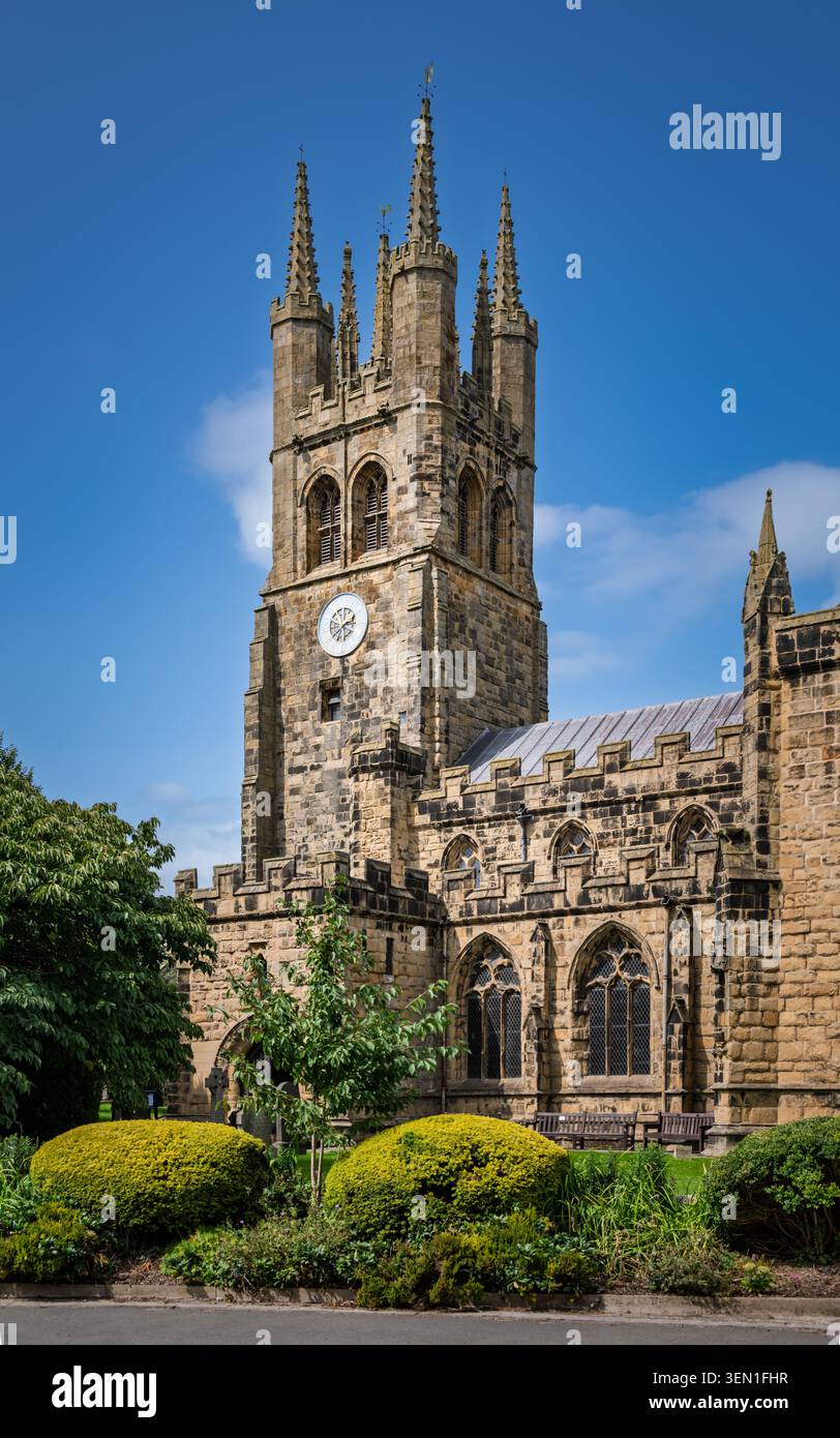Vue portrait vertical mettant en évidence l'imposante tour de pierre de style perpendiculaire et les façades extérieures de l'église Saint-Jean-Baptiste à Tideswell, Derby Banque D'Images