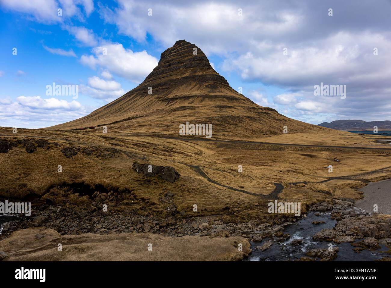 Montagne Kirkjufell s'élevant au-dessus des plaines islandaises sous des nuages dramatiques sur la péninsule de Snæfellsnes Banque D'Images
