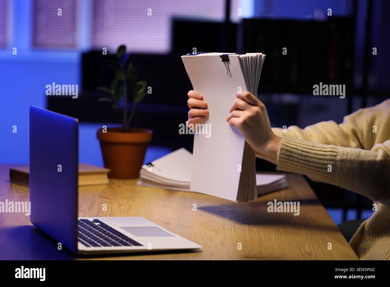 Personne tenant la pile de documents avec ordinateur portable sur le bureau, l'administration des affaires et le concept de travail de bureau, une personne tient une grande pile de document blanc Banque D'Images