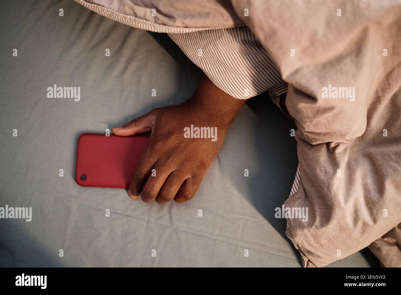 Homme saisissant smartphone dans le lit pour l'habitude d'écran de nuit Banque D'Images