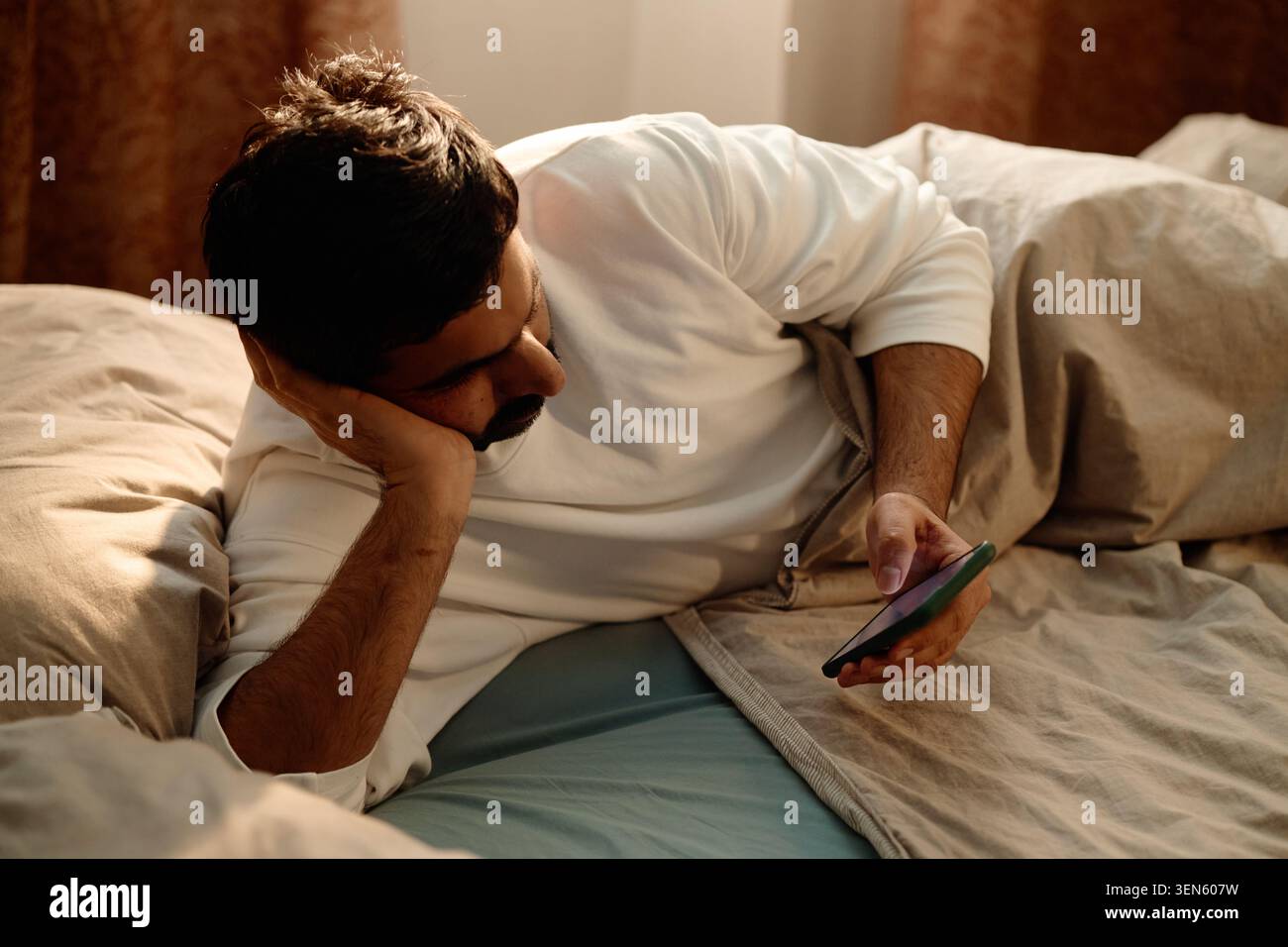 Homme adulte défilant smartphone dans le lit pour la surutilisation de l'écran de nuit tardive Banque D'Images
