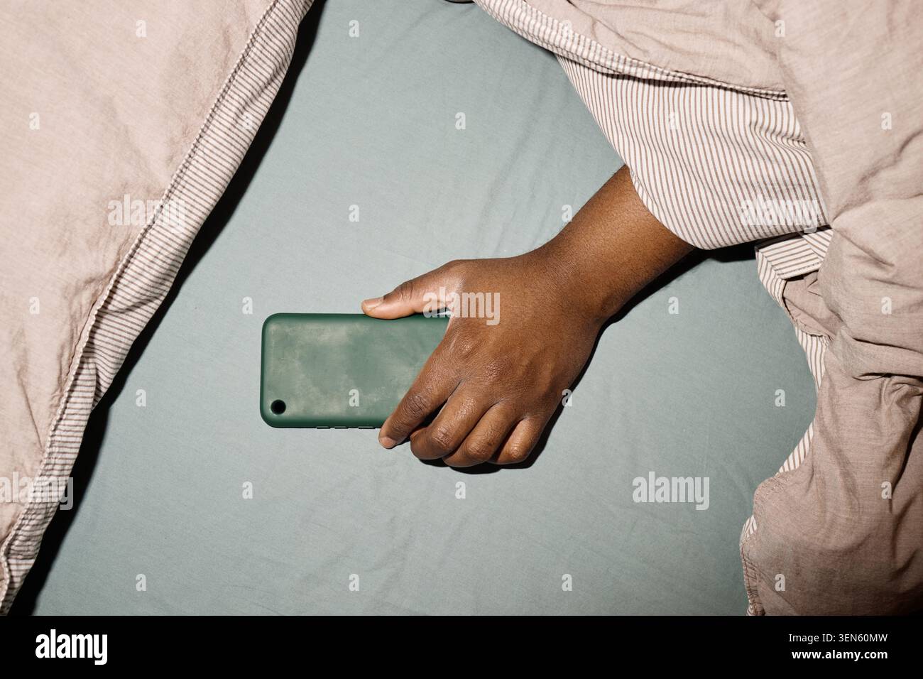 Adulte saisissant le smartphone dans le lit pour dépendance à l'écran Banque D'Images