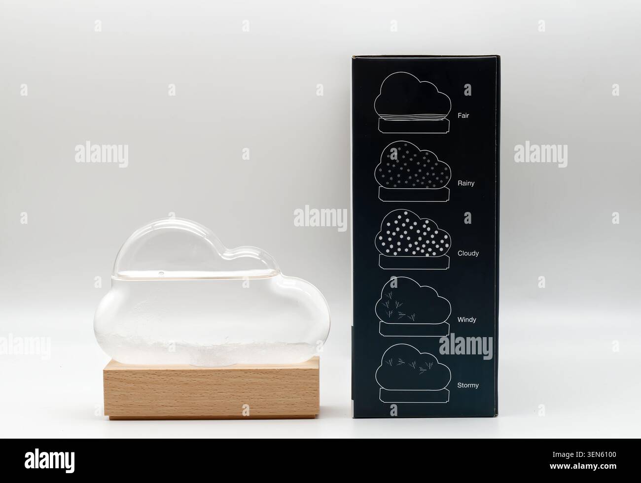Verre de tempête de prévision météorologique en forme de nuage avec des formations cristallines sur une base en bois à côté de sa boîte d'emballage. Banque D'Images