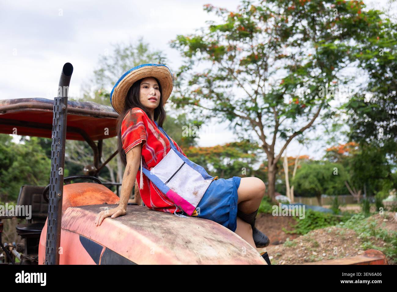 Fermière femme tracteur chapeau rural ferme jardin agriculture, femme asiatique dans le chapeau assis sur le vieux tracteur près du champ de ferme et jardin avec expr calme Banque D'Images