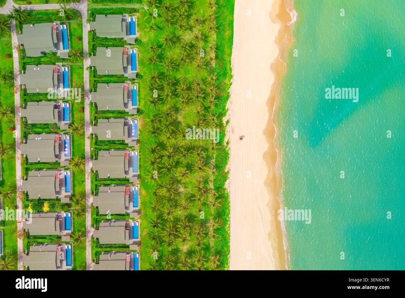 Vue aérienne de dessus de nombreux bâtiments en rangée de lignes identiques avec des jardins densément construits sur la plage de la côte de la mer océan. Maisons côte avec des cocotiers et s blancs Banque D'Images